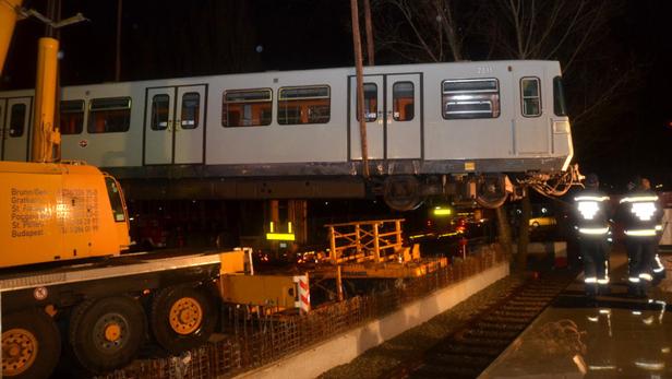 Ein U-Bahn-Waggon wird nachts mit einem Kran auf ein Gleis gehoben.