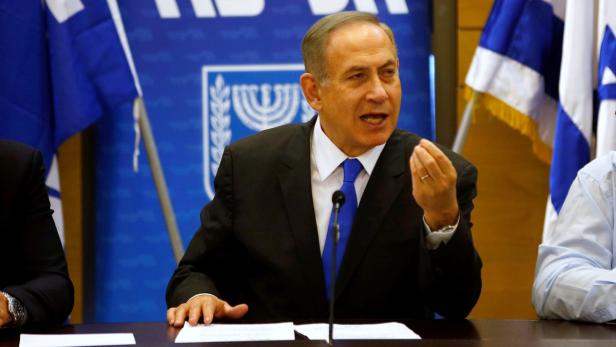 Benjamin Netanjahu spricht vor israelischen Flaggen.