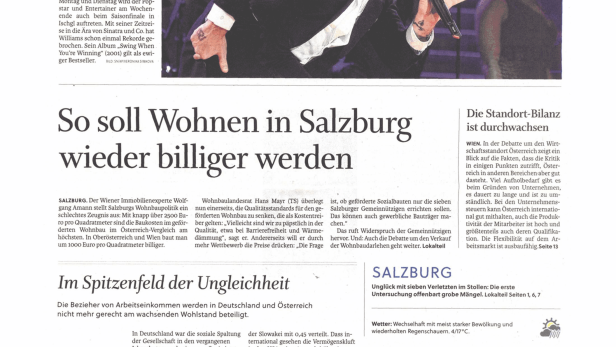 Robbie Williams trägt auf einer Bühne einen Frack und singt in ein Mikrofon.