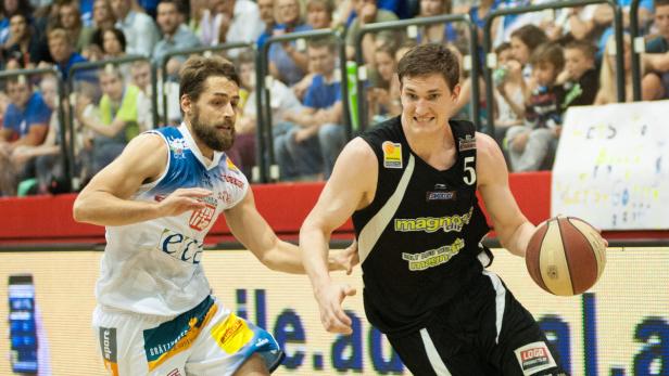 Zwei Basketballspieler während eines Spiels, einer im schwarzen Trikot mit Ball.