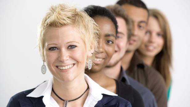 Eine Reihe lächelnder, diverser Personen vor einem weißen Hintergrund.