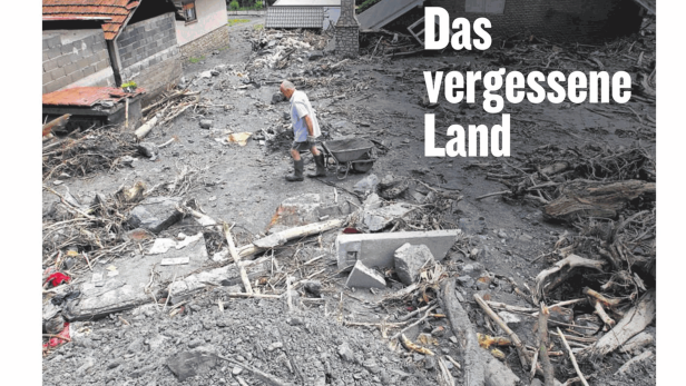 Ein Mann schiebt eine Schubkarre durch eine von Überschwemmungen verwüstete bosnische Landschaft.