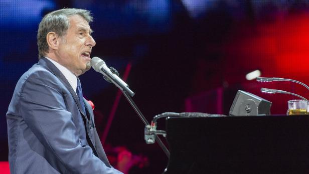 Udo Jürgens singt am Klavier in einem blauen Anzug.