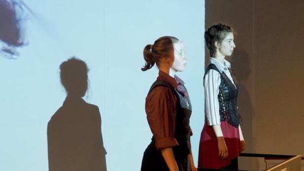 Zwei junge Frauen stehen auf einer Bühne vor einer Projektion.