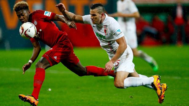 Zwei Fußballspieler kämpfen um den Ball auf dem Spielfeld.