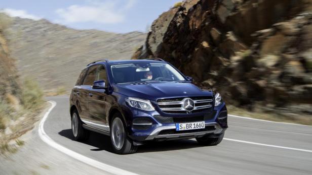 Ein blauer Mercedes-Benz GLE fährt auf einer kurvenreichen Straße in den Bergen.