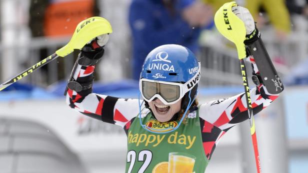 Eine Skirennläuferin jubelt mit erhobenen Armen über ihren Sieg.