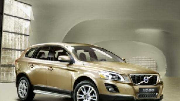 Ein goldener Volvo XC60 steht vor einem modernen Gebäude.
