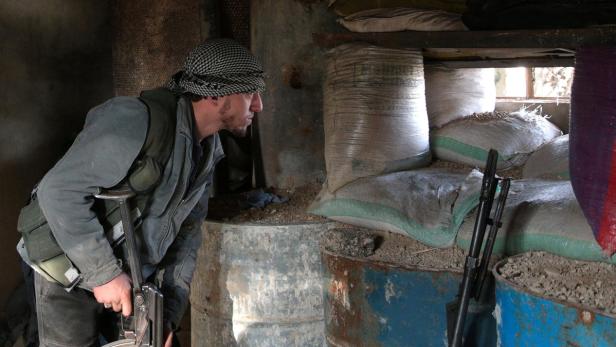 A rebel fighter looks out through sandbags on the