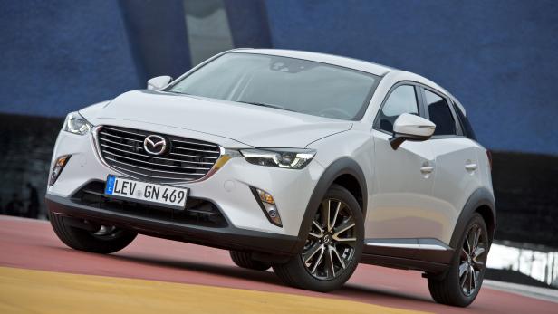 Ein weißer Mazda CX-3 vor einer blauen Wand.
