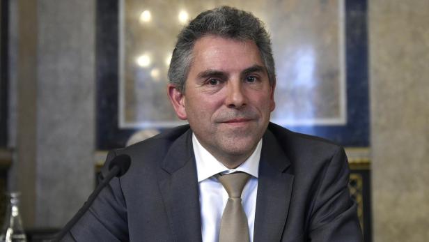 Ein Mann im Anzug sitzt vor einem Mikrofon.