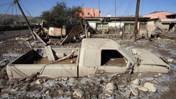 Ein durch Schlamm beschädigter Pickup-Truck steht in einer überfluteten Straße.