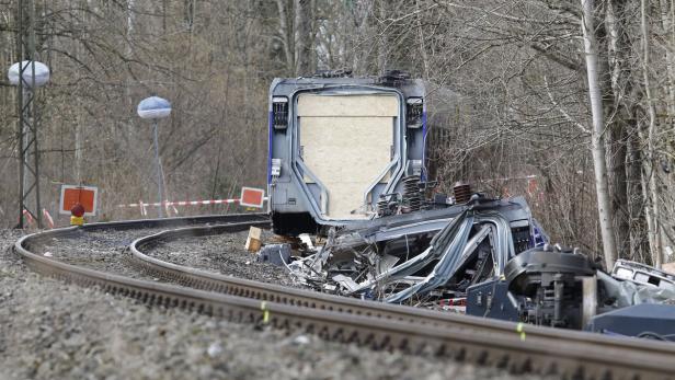 Ein entgleister Zug liegt auf den Gleisen, umgeben von Trümmern.