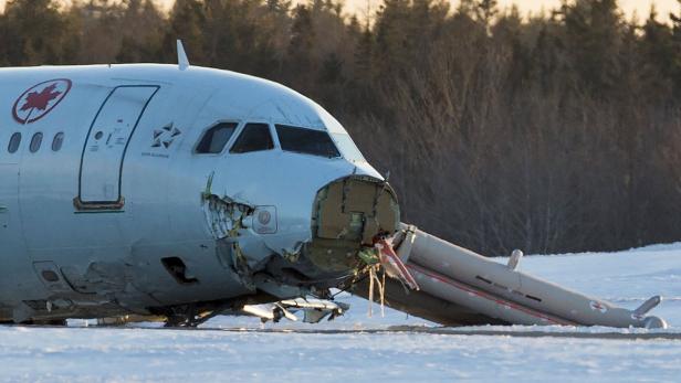 Ein beschädigtes Flugzeug von Air Canada liegt auf einem schneebedeckten Feld.