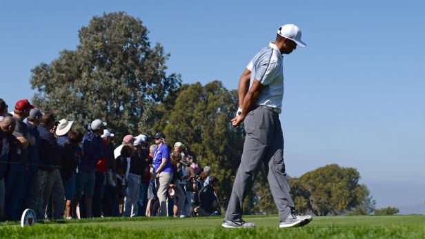 Tiger Woods geht mit gesenktem Kopf an einer Zuschauermenge vorbei.