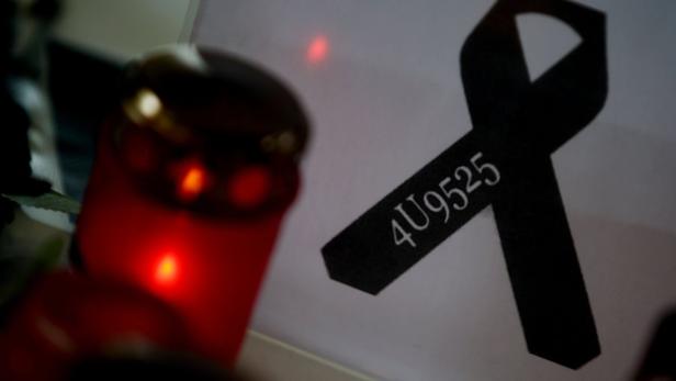 Eine brennende Kerze neben einer schwarzen Schleife mit der Aufschrift „4U9525“.