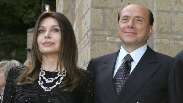 Silvio Berlusconi mit einer Frau, die eine auffällige Halskette trägt.