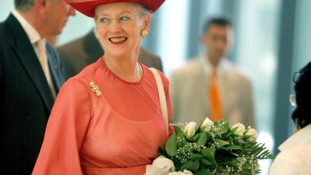 Königin Margrethe II. von Dänemark mit einem roten Hut und einem Blumenstrauß.