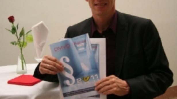 Ein Mann im Anzug präsentiert Broschüren mit dem Aufdruck „OMVG 2011“.