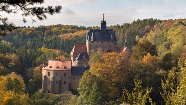 Die mittelalterliche Burgruine thront inmitten eines herbstlichen Waldes.