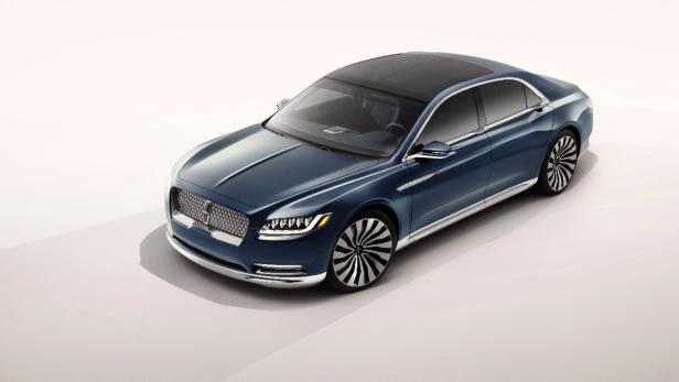 Ein blauer Lincoln Continental mit Panoramadach vor einem neutralen Hintergrund.