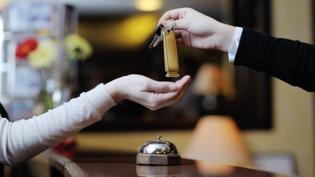 Eine Person erhält einen Schlüssel an einem Empfangstresen.