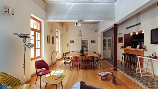 Ein geräumiges Wohnzimmer mit Holzboden, einem Esstisch und einer Bar.