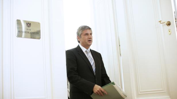 Ein Mann im Anzug steht vor einer Tür mit dem Schild „Zum Bundeskanzler“.