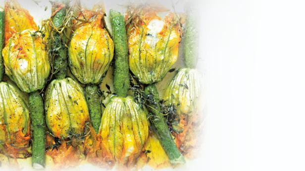 Gefüllte Zucchiniblüten und Zucchini liegen auf einem Teller.