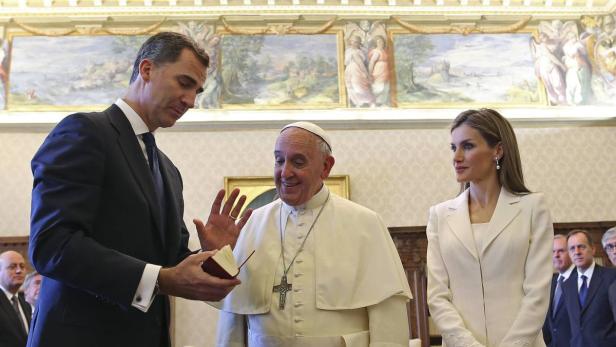 König Felipe von Spanien überreicht Papst Franziskus ein Buch, während Königin Letizia zusieht.