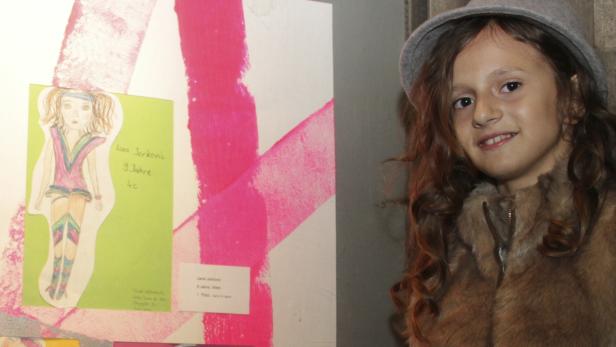 Ein Mädchen mit Hut steht neben einer Zeichnung von Lana Jerkovic, 9 Jahre alt.