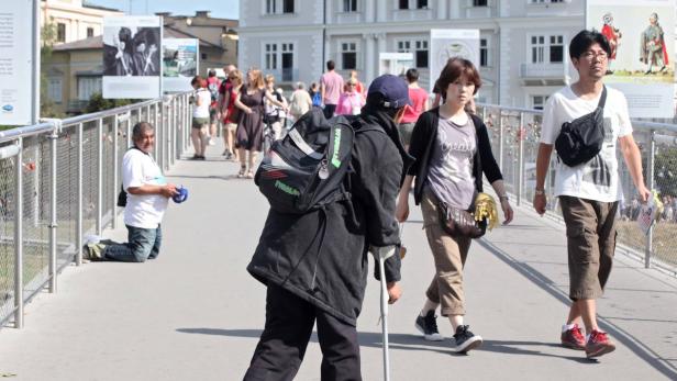 Viele Einheimische und Touristen fühlen sich von Bettlern, die (wie hier auf dem Makartsteg in der Salzburger Innenstadt) um Almosen bitten, bedroht.