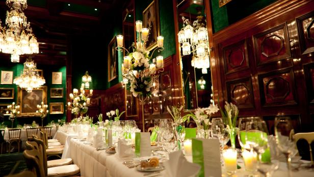 Ein festlich gedeckter Tisch in einem eleganten Speisesaal mit Kronleuchtern.