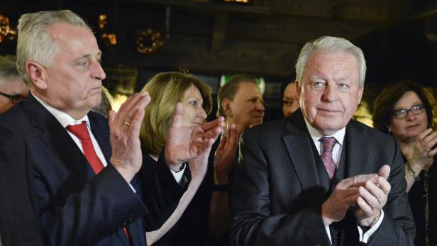 Mehrere Personen, darunter zwei Männer im Anzug, applaudieren.