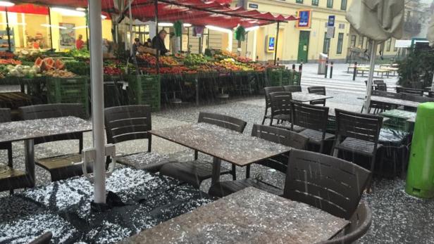 Ein Marktstand und Tische sind von Hagel bedeckt.