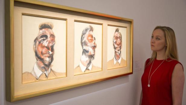 Eine Frau betrachtet ein Triptychon mit Porträts von Francis Bacon in einer Kunstgalerie.
