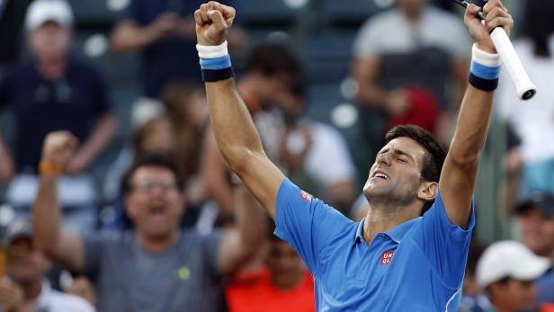 Novak Đoković feiert mit erhobenen Armen einen Sieg auf dem Tennisplatz.