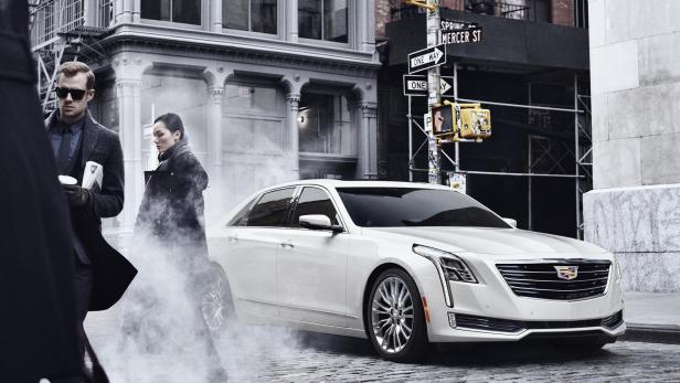 Ein weißer Cadillac fährt durch eine Straße in der Stadt.