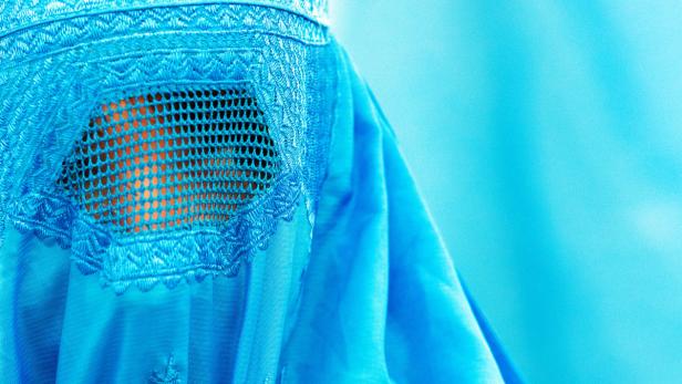 Nahaufnahme einer hellblauen Burka mit besticktem Sichtfenster.