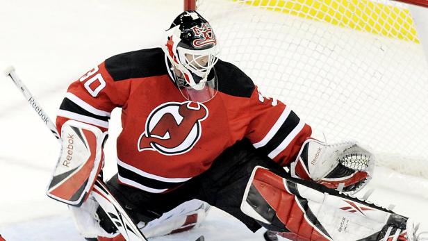 Ein Eishockeytorwart der New Jersey Devils in roter Spielkleidung vor dem Netz.