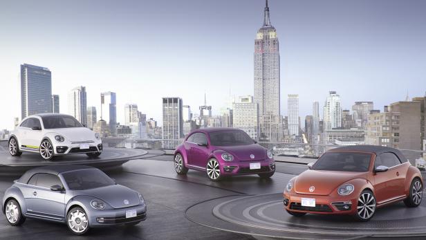 Vier verschiedenfarbige VW Käfer vor der Skyline von New York mit dem Empire State Building.