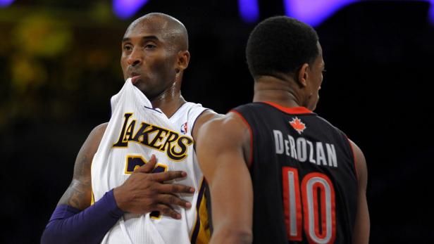 Kobe Bryant hält sein Lakers-Trikot, während DeMar DeRozan im Hintergrund steht.