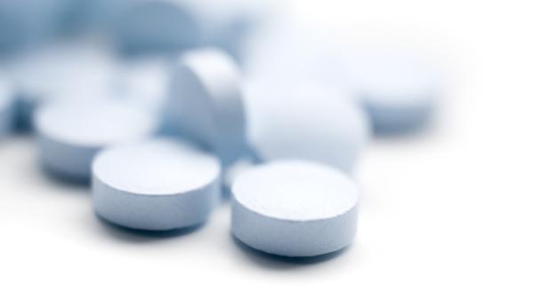 Nahaufnahme von blauen, runden Tabletten auf einem weißen Hintergrund.