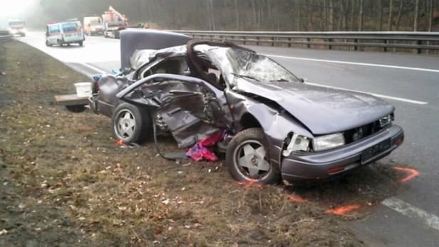 Ein schwer beschädigtes Auto steht nach einem Unfall am Straßenrand.