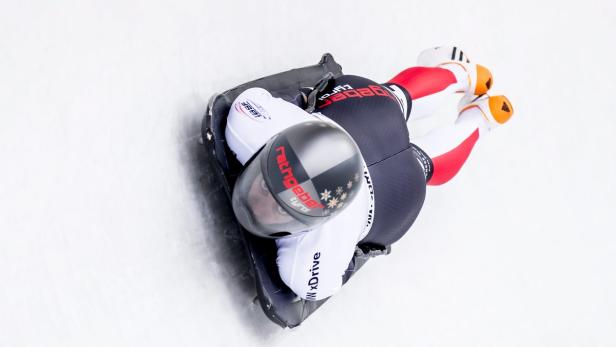Ein Skeleton-Athlet liegt auf seinem Schlitten auf einer Eisbahn.
