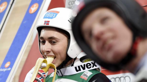 Ein Rennrodler isst eine Banane vor dem Start.