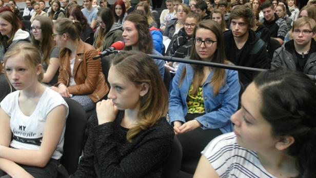 Eine Gruppe junger Leute sitzt aufmerksam in einer Veranstaltung.