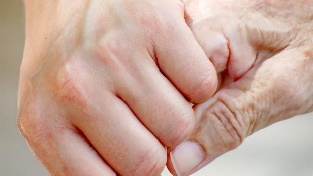 Eine ältere Hand hält eine jüngere Hand fest.
