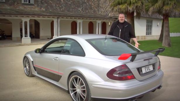 Ein Mann steht neben einem silbernen Mercedes-Benz mit dem Nummernschild „EVIL“.