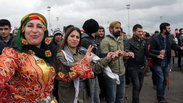 Eine Gruppe von Menschen tanzt traditionelle kurdische Tänze im Freien.